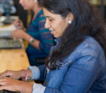 women sitting writing on laptop mug