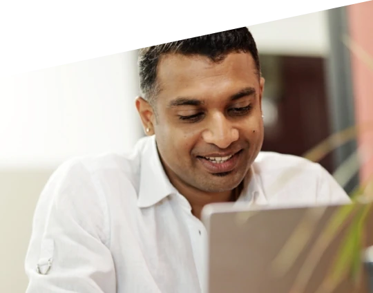Smiling man working on a laptop in a bright indoor setting