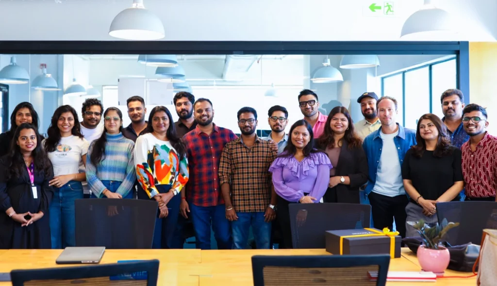 Large team of coworkers posing together in a modern open-plan office