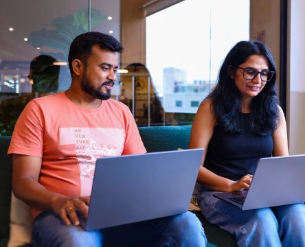 Coworkers working on laptops in a modern office lounge