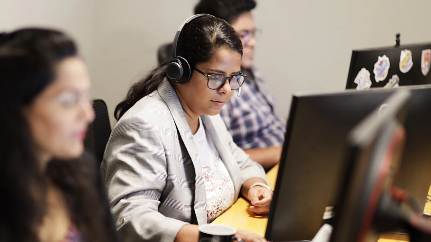 three people work at a computer desk