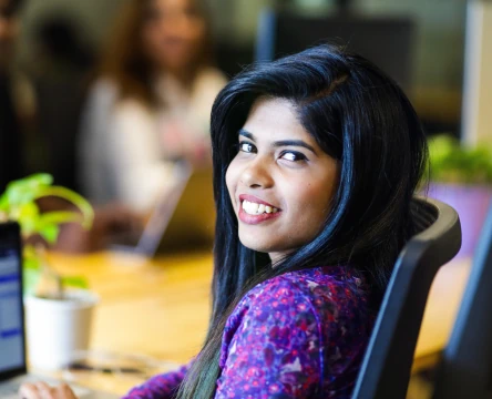 Woman smiling while sitting at a desk in an office.