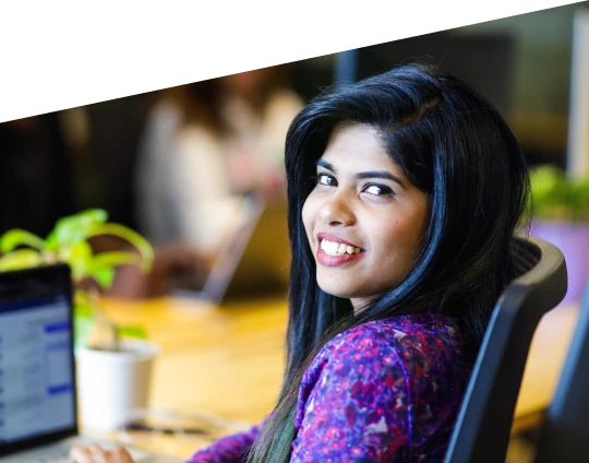Woman smiling while sitting at a desk in an office.