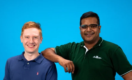 two colleagues posing against a blue background
