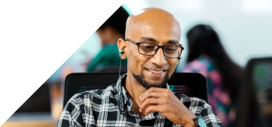 man using a laptop while wearing earphones in an office