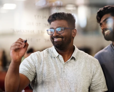 Employee writing on a glass board in an office