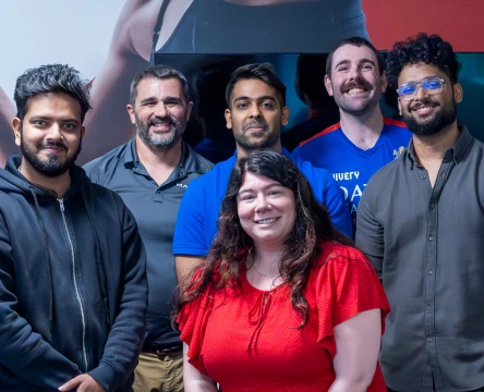 Team members posing together indoors in a modern workplace