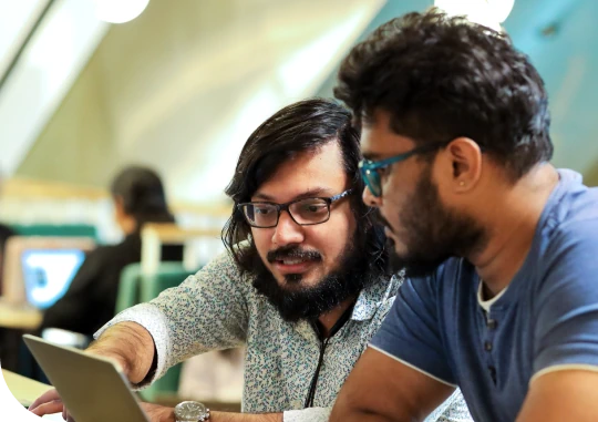 Two colleagues working together at a laptop in an office