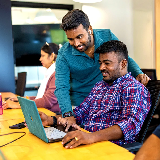 Two software engineers reviewing code together on a laptop in Bangalore, India