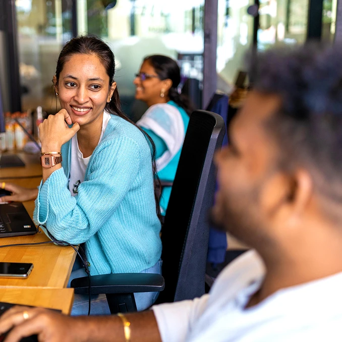 woman smiling at her coworker while working at a desk in a modern office