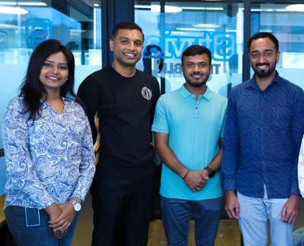 Team members standing in a modern office and smiling at the camera