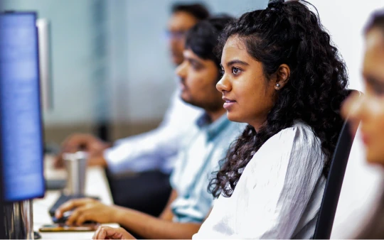 Woman sitting in an office with coworkers in the background