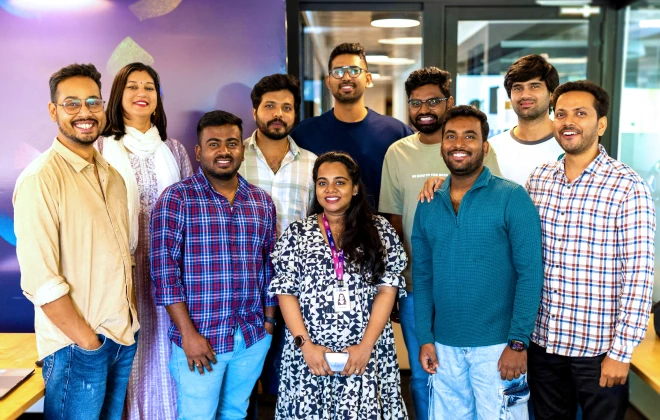 Group photo of nine colleagues smiling indoors