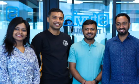 Team members standing in a modern office and smiling at the camera