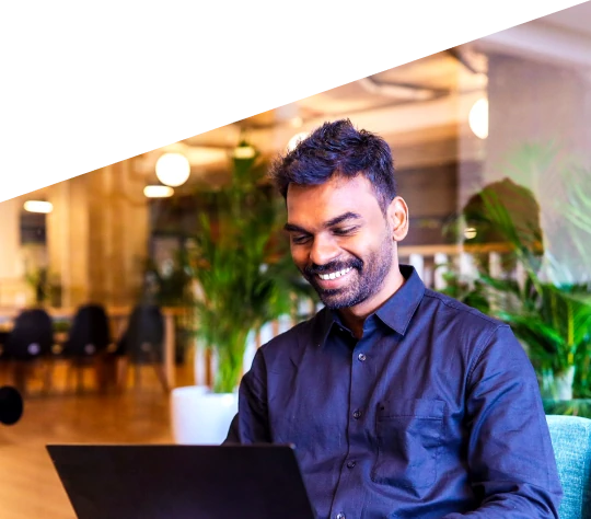 Smiling man using a laptop in a modern office