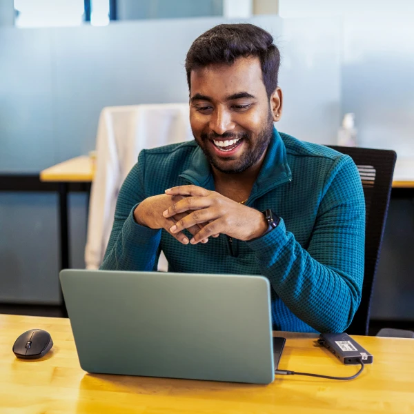 Man smiling while working on a laptop in the office